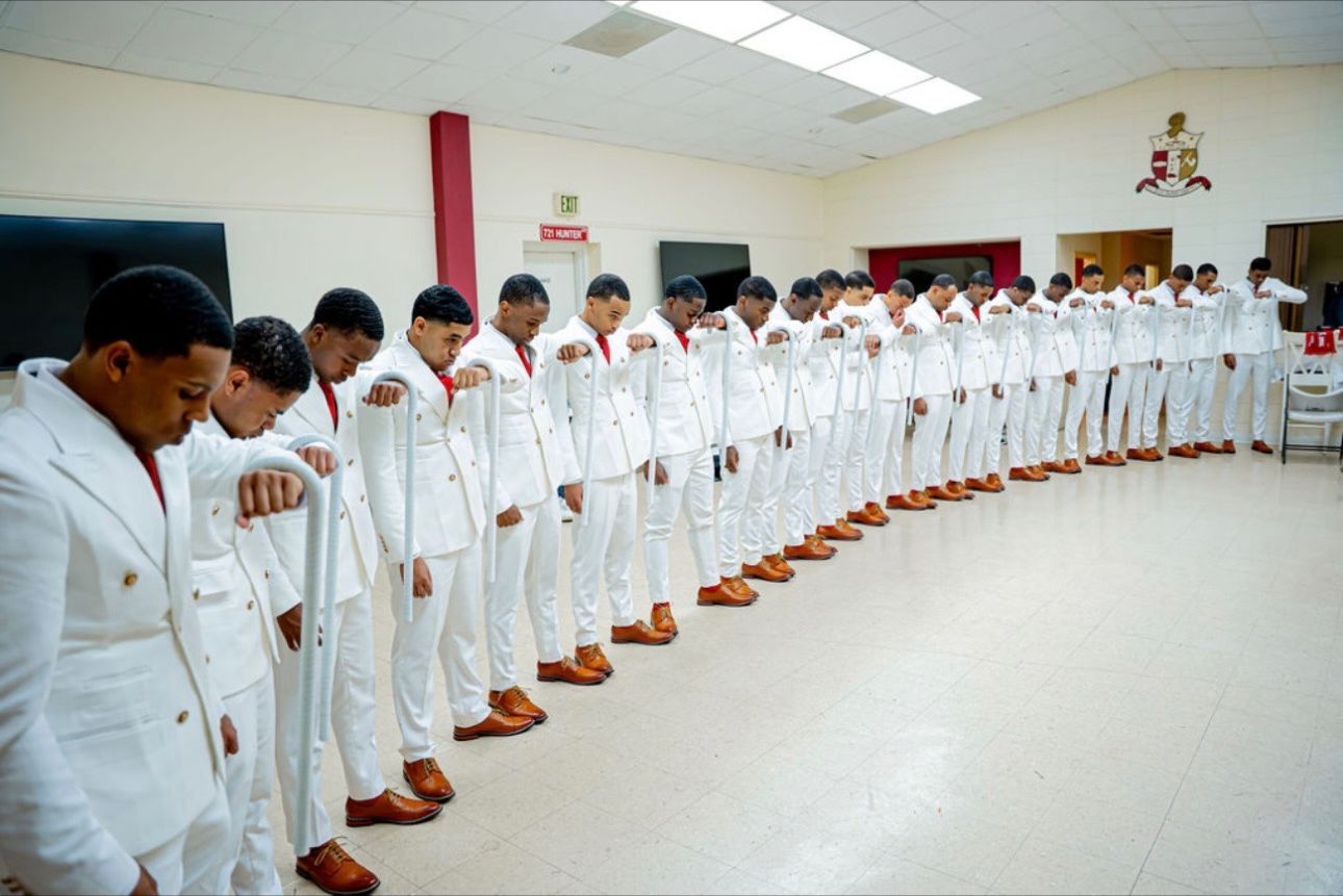 The full line standing in a curved row, heads bowed, inside the chapter hall