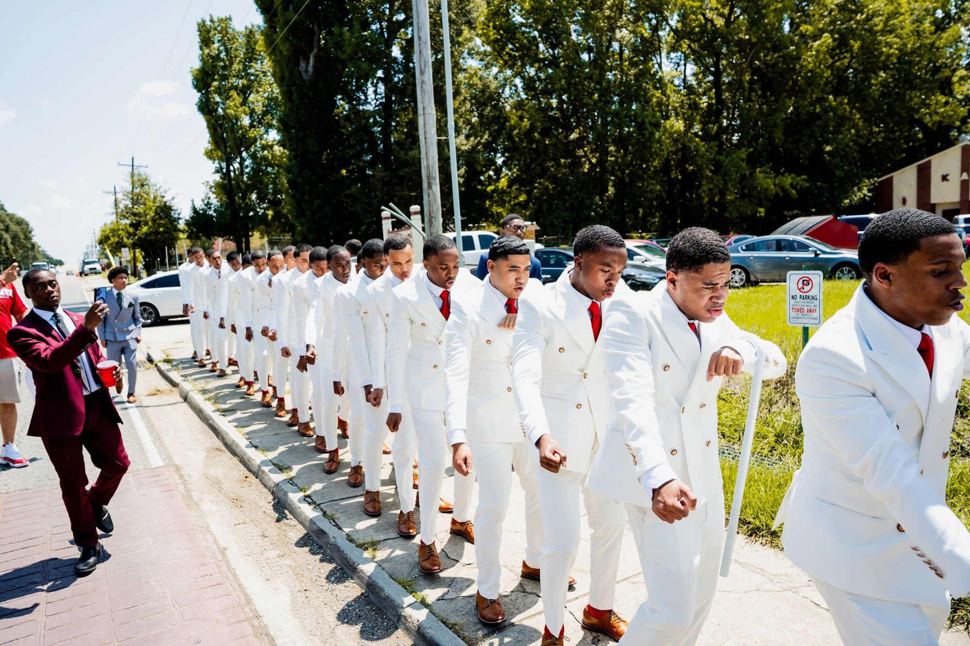 The SWIFT 22 line marching single file down the street in white suits